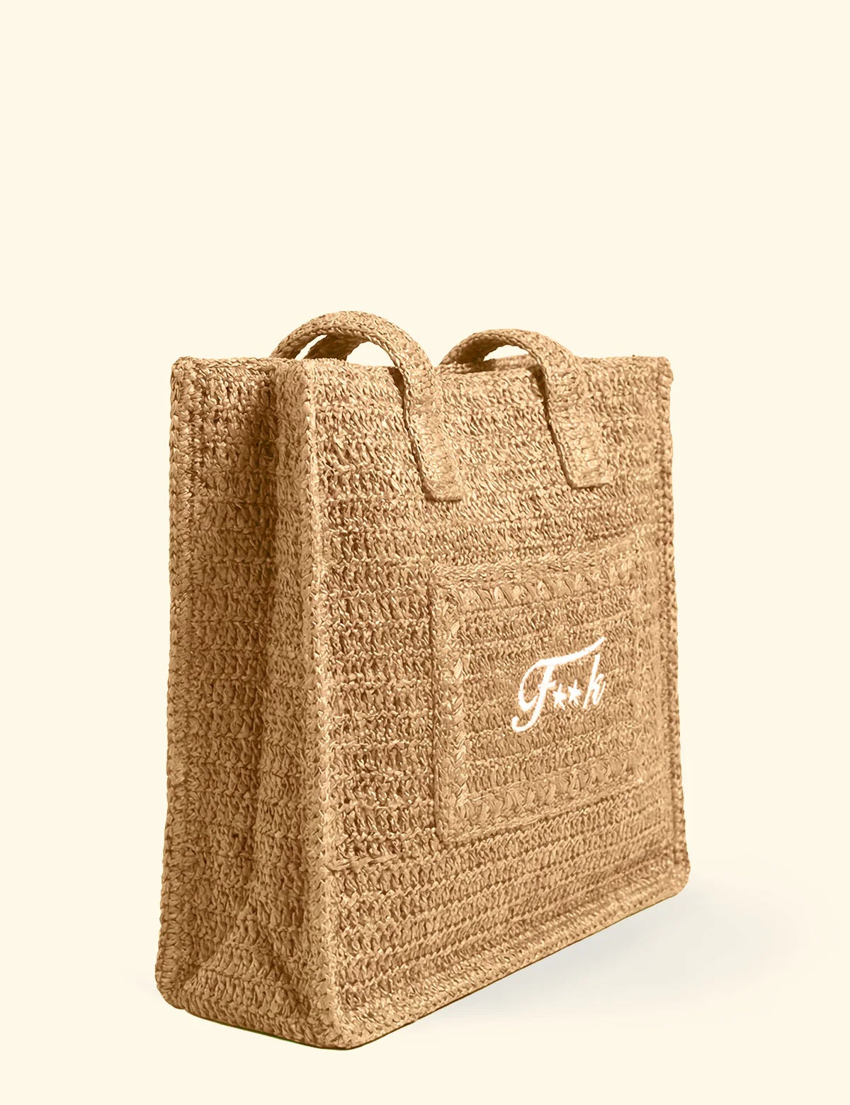 Borsa mare in rafia modello tote bag del brand F**K con logo bianco ricamato e chiusura a bottone, vista di tre quarti.