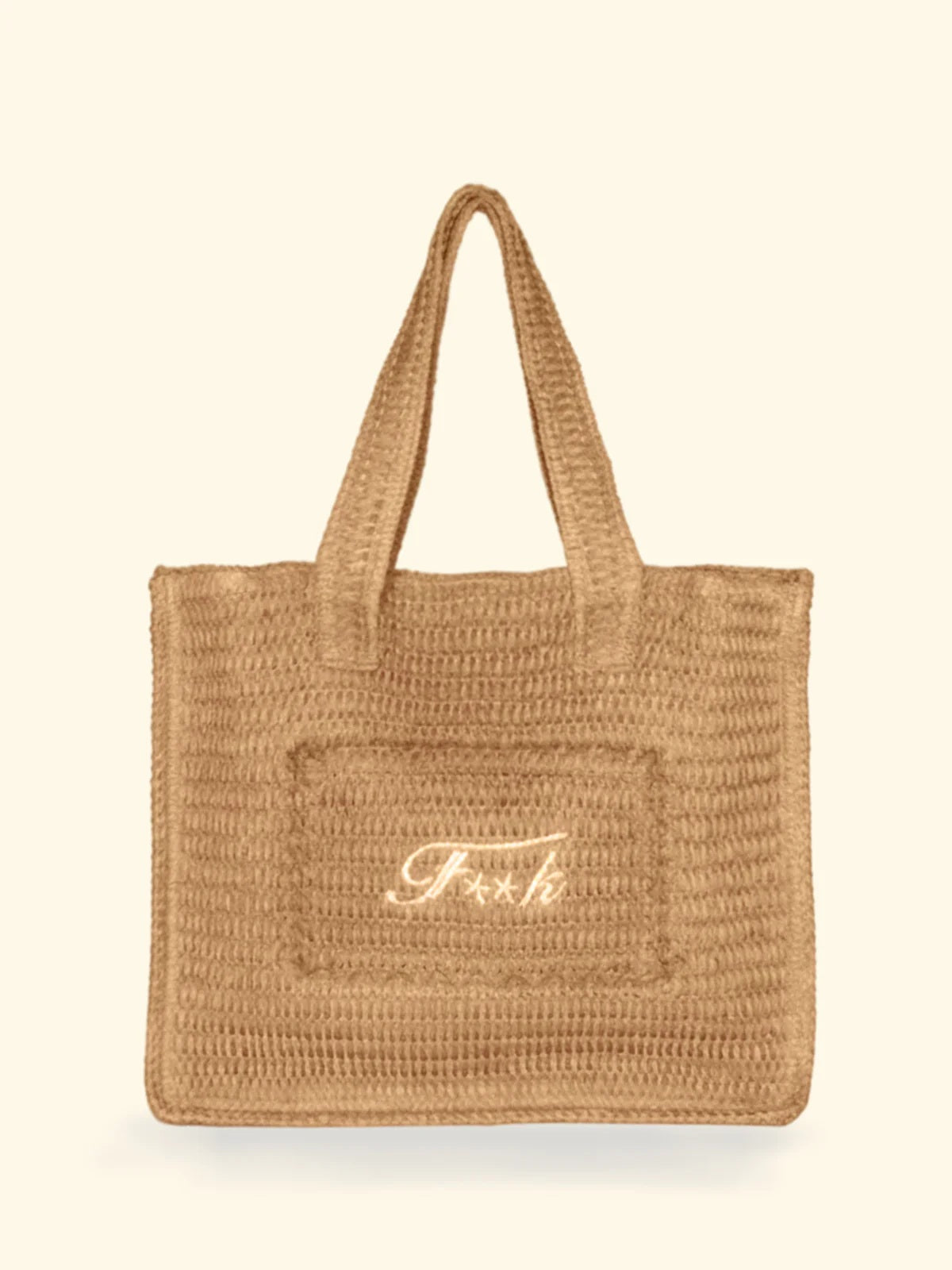Borsa mare in rafia modello Tote Bag del brand F**K con scritta ricamata color panna su fondo neutro.