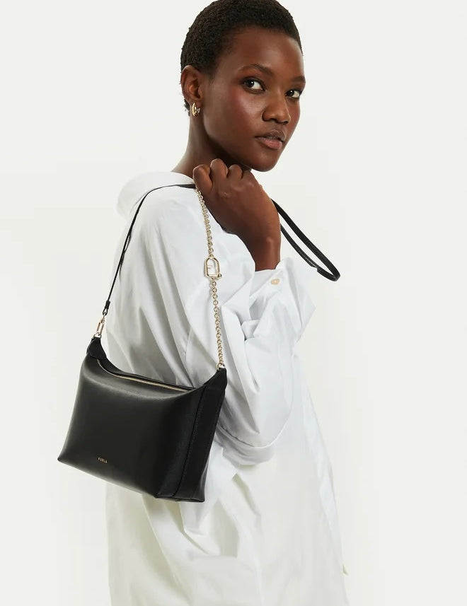 Mini crossbody Furla indossata da una modella con manico a catena in pelle di vitello, elegante e pratica.